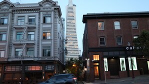 A multi-story building with a fire escape, a tall skyscraper in the background, and a brick building with a storefront. - Europa Hotel (San Francisco)