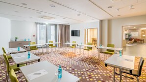 Ein Hotelkonferenzraum mit mehreren Tischen, Stühlen und Teppichboden.