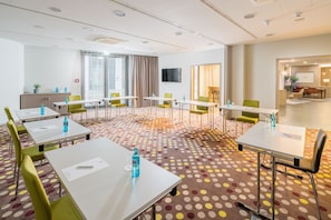 Een hotelconferentiezaal met meerdere tafels, stoelen en een vloerbedekking.