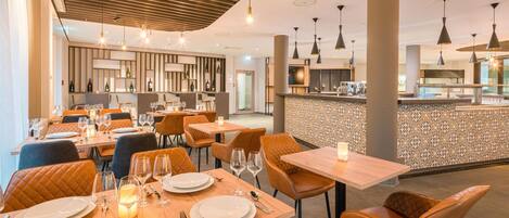 Un restaurant avec des tables en bois, des chaises en cuir et des luminaires suspendus.