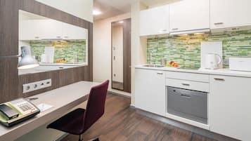 A modern kitchen with white cabinets, a built-in dishwasher, and a green-tiled backsplash.