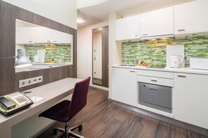 Una cocina moderna con gabinetes blancos, lavavajillas integrado y salpicadero de azulejos verdes.