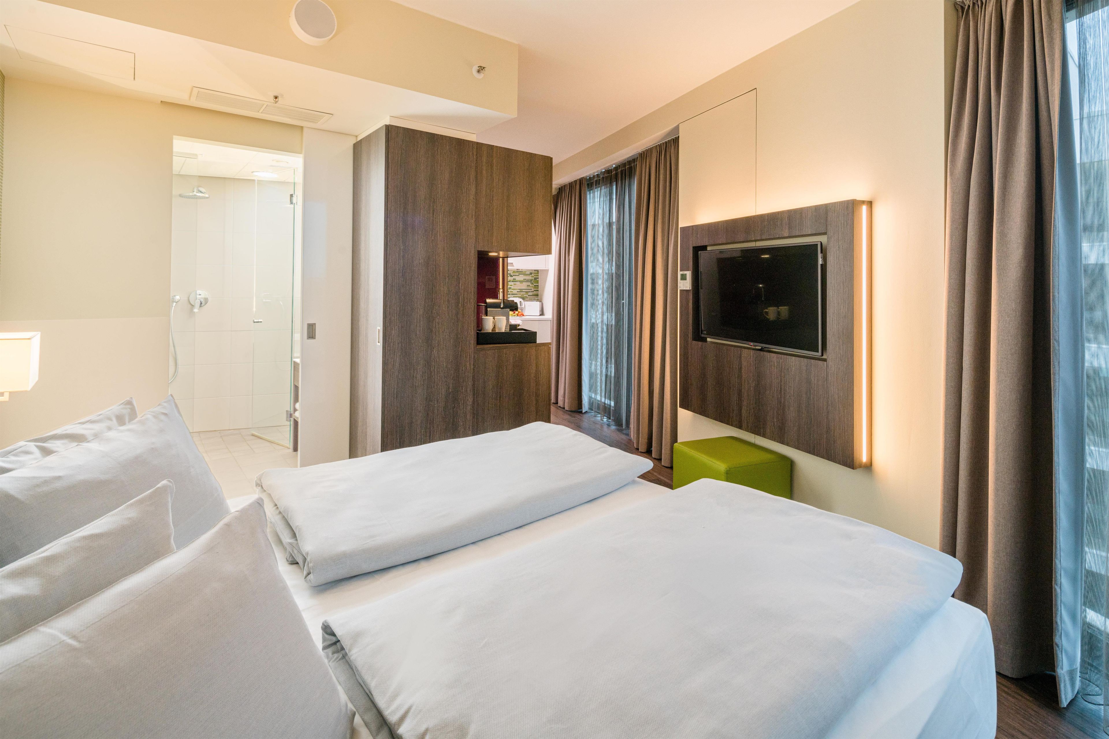 Habitación de hotel con dos camas, televisión, una zona de estar pequeña y baño.