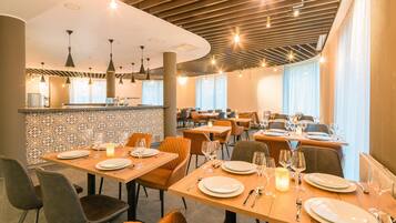 A restaurant with multiple dining tables, chairs, and a bar area.