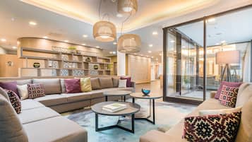 A modern living room with a sectional sofa, a coffee table, and a bookshelf.