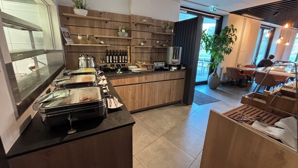 Eine moderne Küche mit Speisenausgabe in Buffetform, Holzschränken und verschiedenen Küchengeräten.