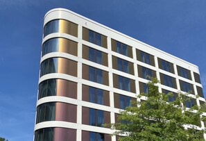 Um edifício moderno com fachada curva, grandes janelas e céu azul.