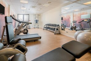 Een sportschool met trainingsapparatuur, waaronder loopbanden, gewichten en krachtapparaten.