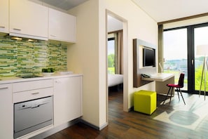Een moderne keuken met witte kasten, een groen-wit betegelde achterwand en een ingebouwde oven.