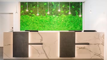 A reception desk with a green moss wall and pendant lighting.