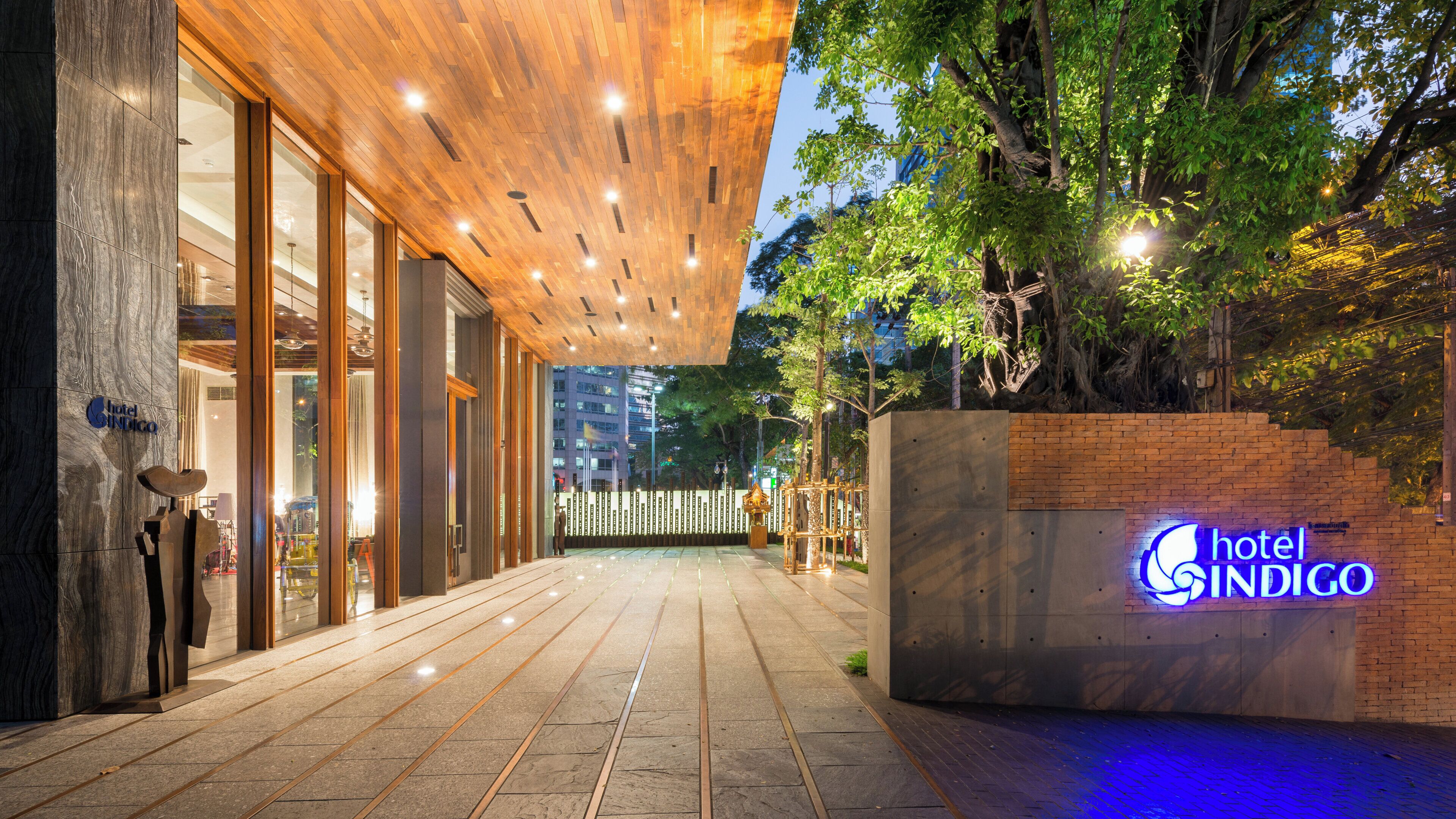 A hotel entrance with a modern design, a wooden ceiling, and a sign indicating the hotel name.