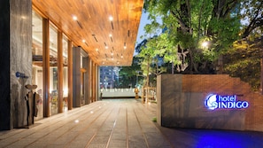 A hotel entrance with a modern design, a wooden ceiling, and a sign indicating the hotel name. - Hotel Indigo Bangkok Wireless Road by IHG (Bangkok)