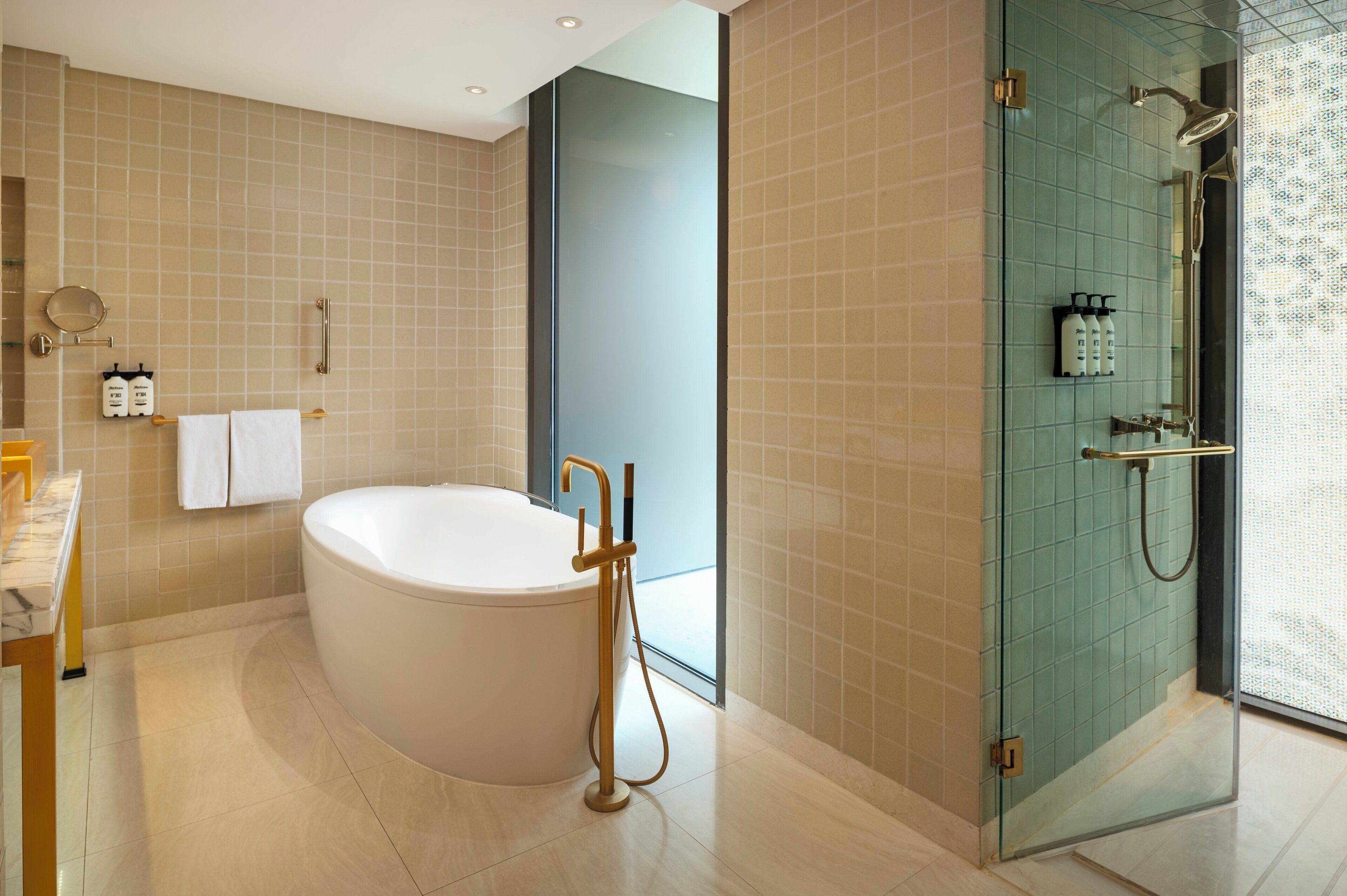A modern bathroom with a freestanding bathtub, a glass shower enclosure, and a marble-topped vanity.