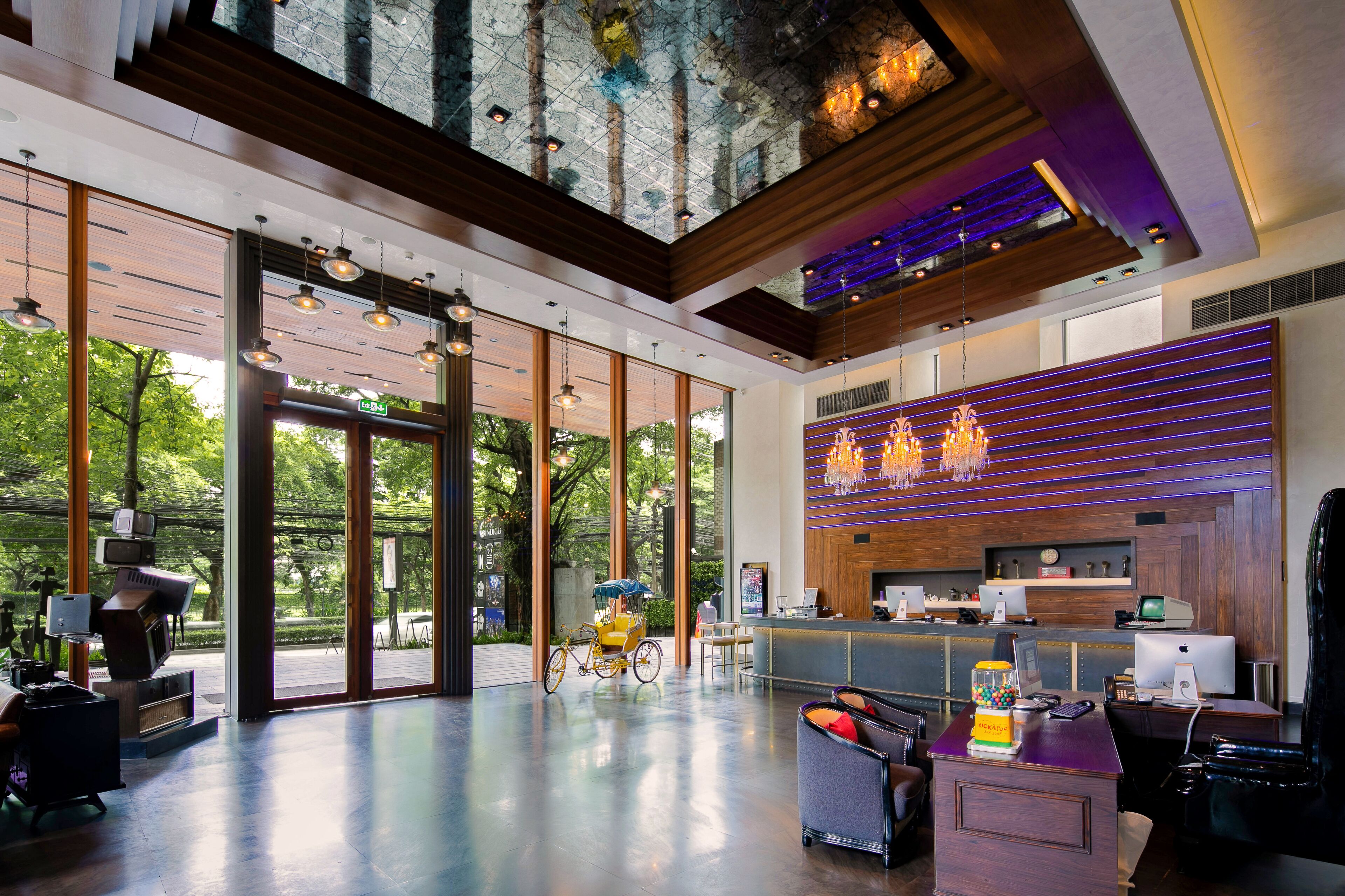 Un lobby moderno con mostrador de recepción, zona de estar y grandes ventanales con vista a un jardín.