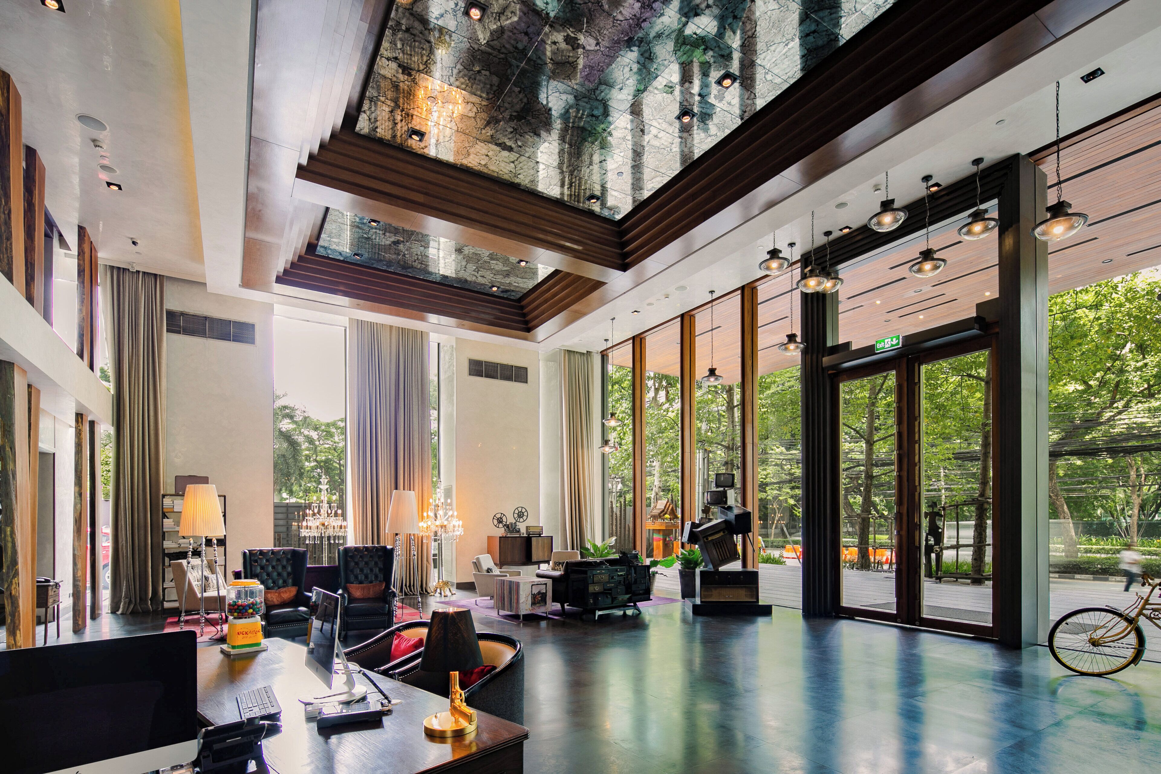 A spacious hotel lobby with a high ceiling, large windows, and a view of the outdoors.