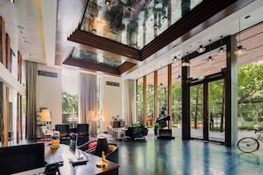 Un hall d’hôtel spacieux, doté d’un haut plafond, de grandes fenêtres et offrant une vue sur l’extérieur.