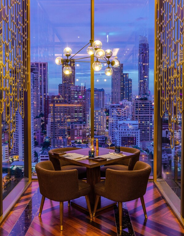 Un comedor con vistas a la ciudad, una mesa con cuatro sillas y una araña.