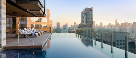 Una piscina al aire libre, sombrillas, sillones reclinables de piscina