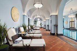 Un couloir d’hôtel avec des fauteuils confortables, une piscine et des œuvres d’art décoratives sur les murs.