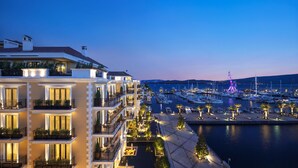A waterfront hotel with multiple balconies, a marina with boats, and a view of the water. - Regent Porto Montenegro (Tivat)