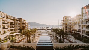 A marina with boats, a pool, and modern buildings with balconies. - Regent Porto Montenegro (Tivat)