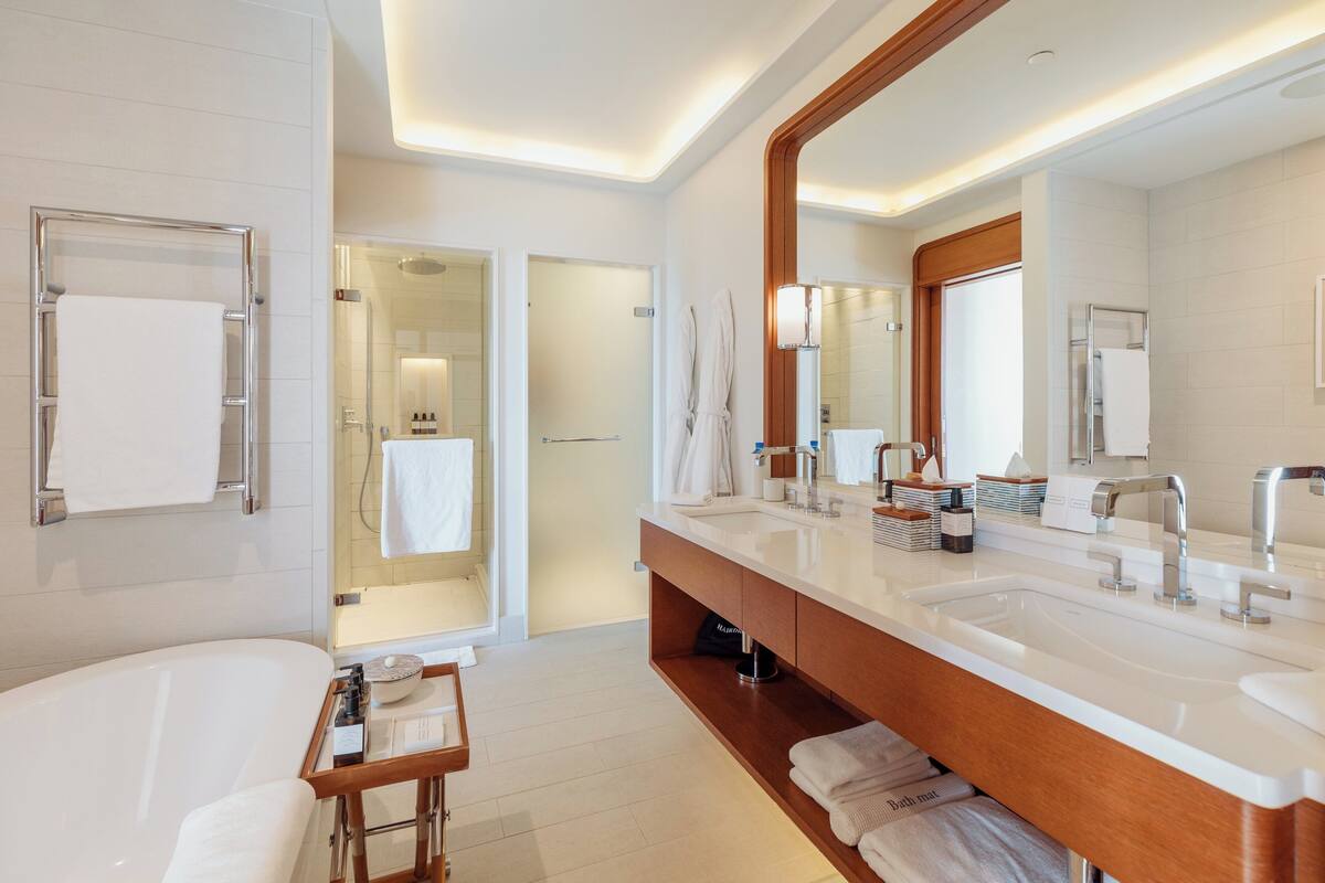A modern bathroom with a large bathtub, dual sinks, and a vanity with storage.