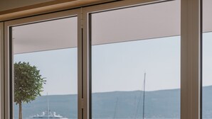 A balcony with a view of a marina, featuring white furniture and a potted plant. - Regent Porto Montenegro (Tivat)