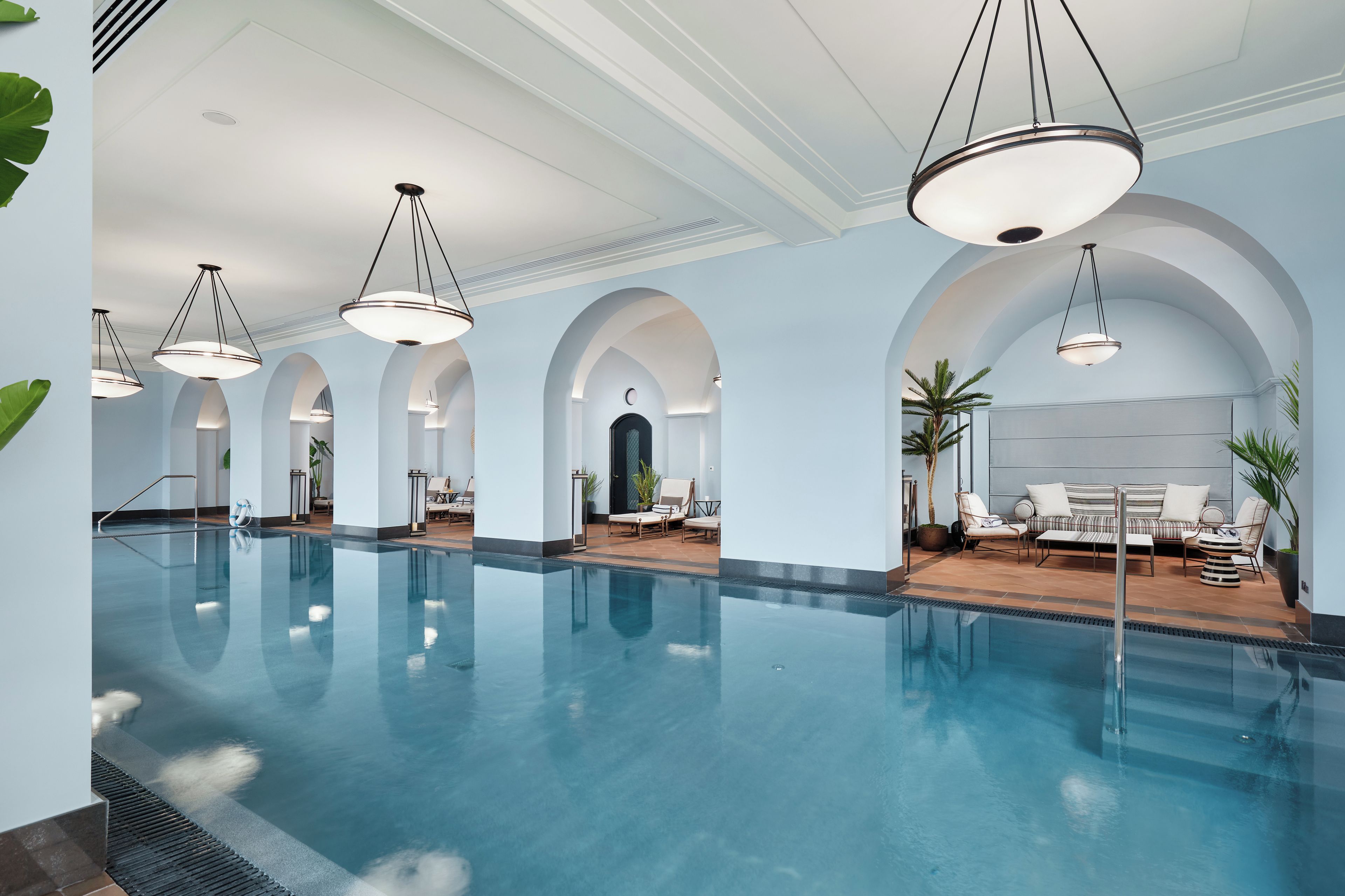 Une grande piscine intérieure dotée de nombreux espaces de détente et d’un éclairage moderne.