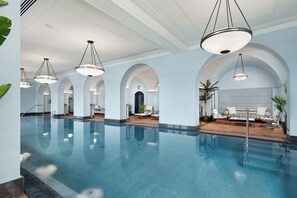 Une grande piscine intérieure dotée de nombreux espaces de détente et d’un éclairage moderne.