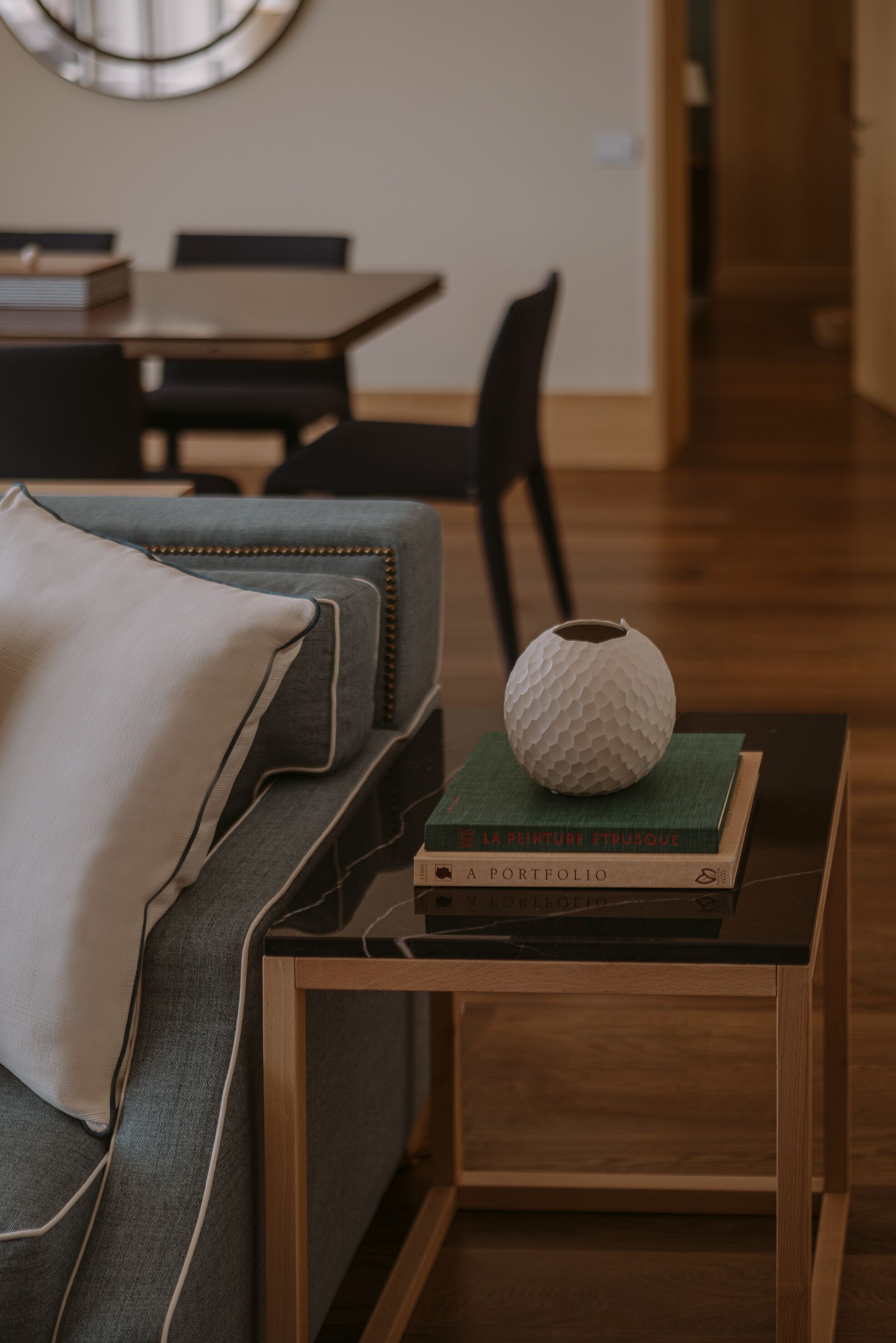 Een moderne woonkamer met een bank, een salontafel en een eettafel op de achtergrond.