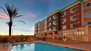 A hotel with a swimming pool, multiple floors, and a palm tree. - Courtyard by Marriott Victoria (Victoria)