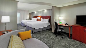 A hotel room with two beds, a desk with a computer, a TV, and a sofa. - Courtyard by Marriott Victoria (Victoria)