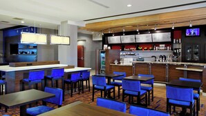 A modern restaurant with blue chairs, wooden tables, and a bar area. - Courtyard by Marriott Victoria (Victoria)