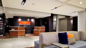 A modern lobby with a reception desk, seating area, and a patterned rug. - Courtyard by Marriott Victoria (Victoria)