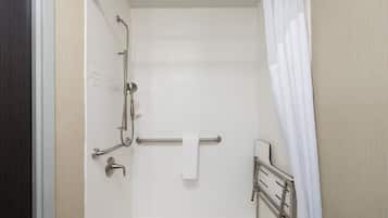 A bathroom with white tiles, a shower with a grab bar, and a towel rack.