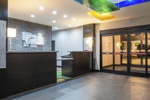 A hotel reception area with a modern design, including a reception desk, a wall-mounted sign, and a glass door with emergency instructions. - Holiday Inn Express & Suites Norman by IHG (Norman)