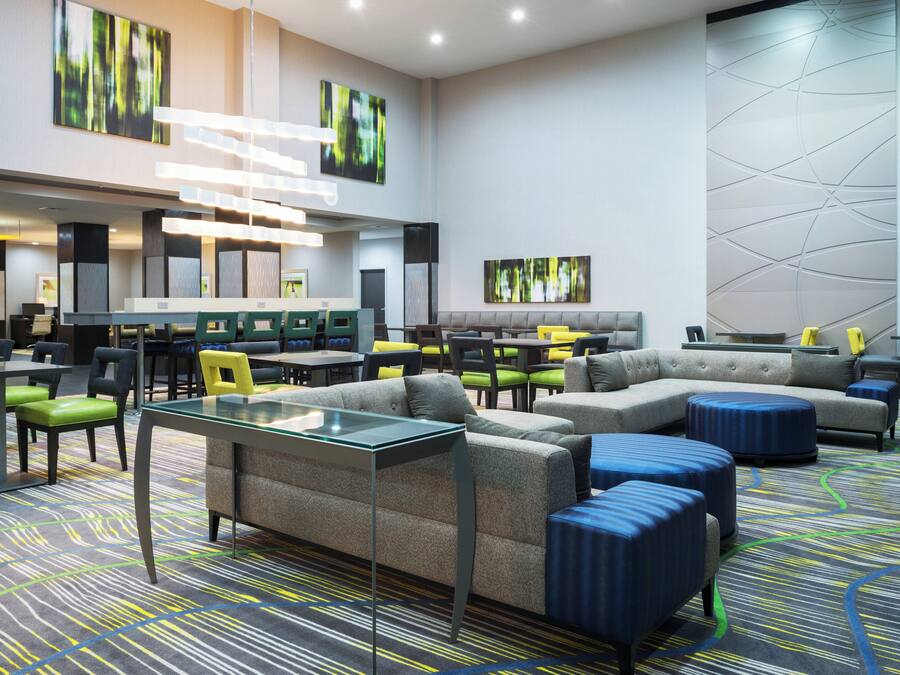 A modern hotel lobby with a seating area, tables, and artwork on the walls.