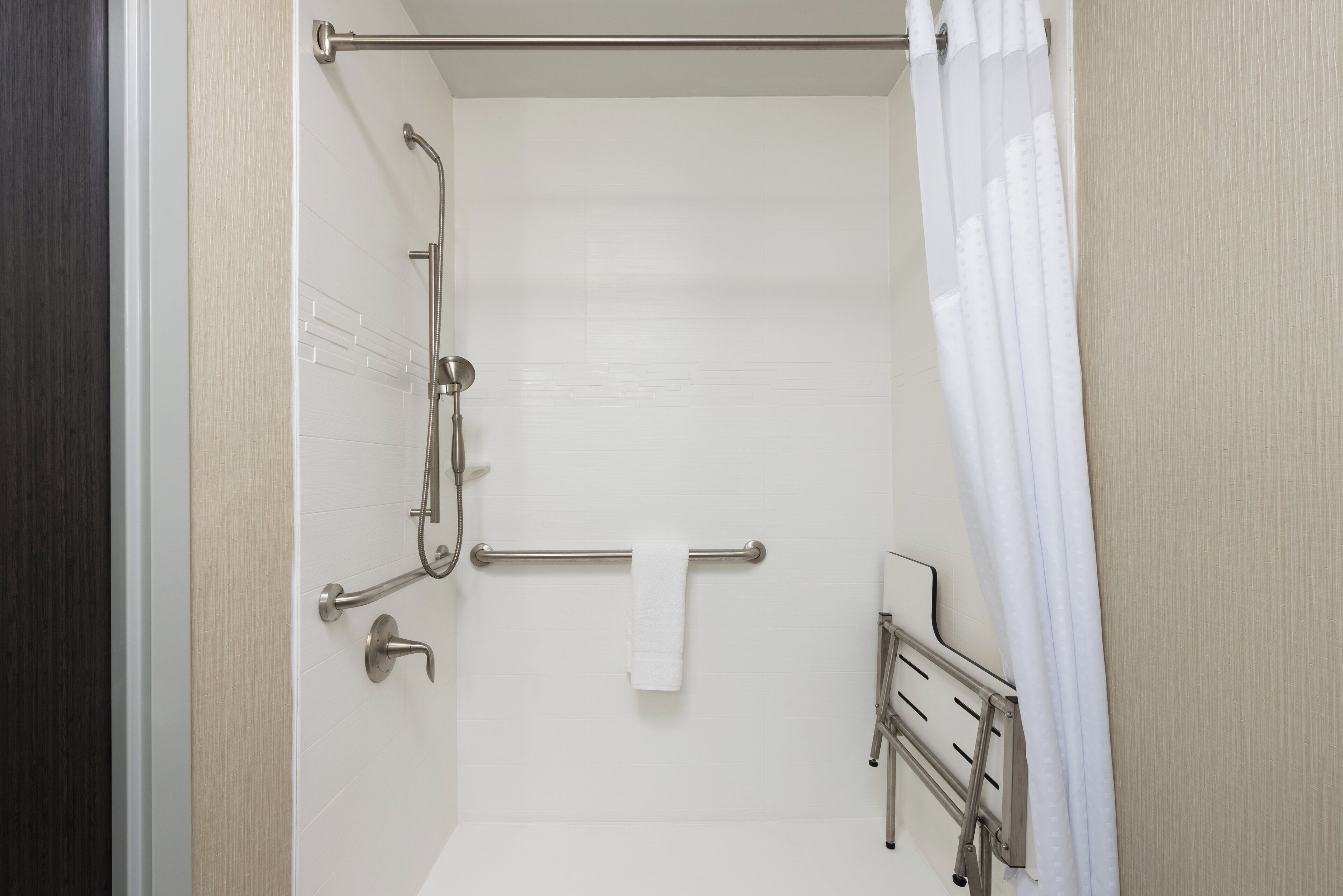 A shower with a grab bar, a towel rack, and a shower curtain.