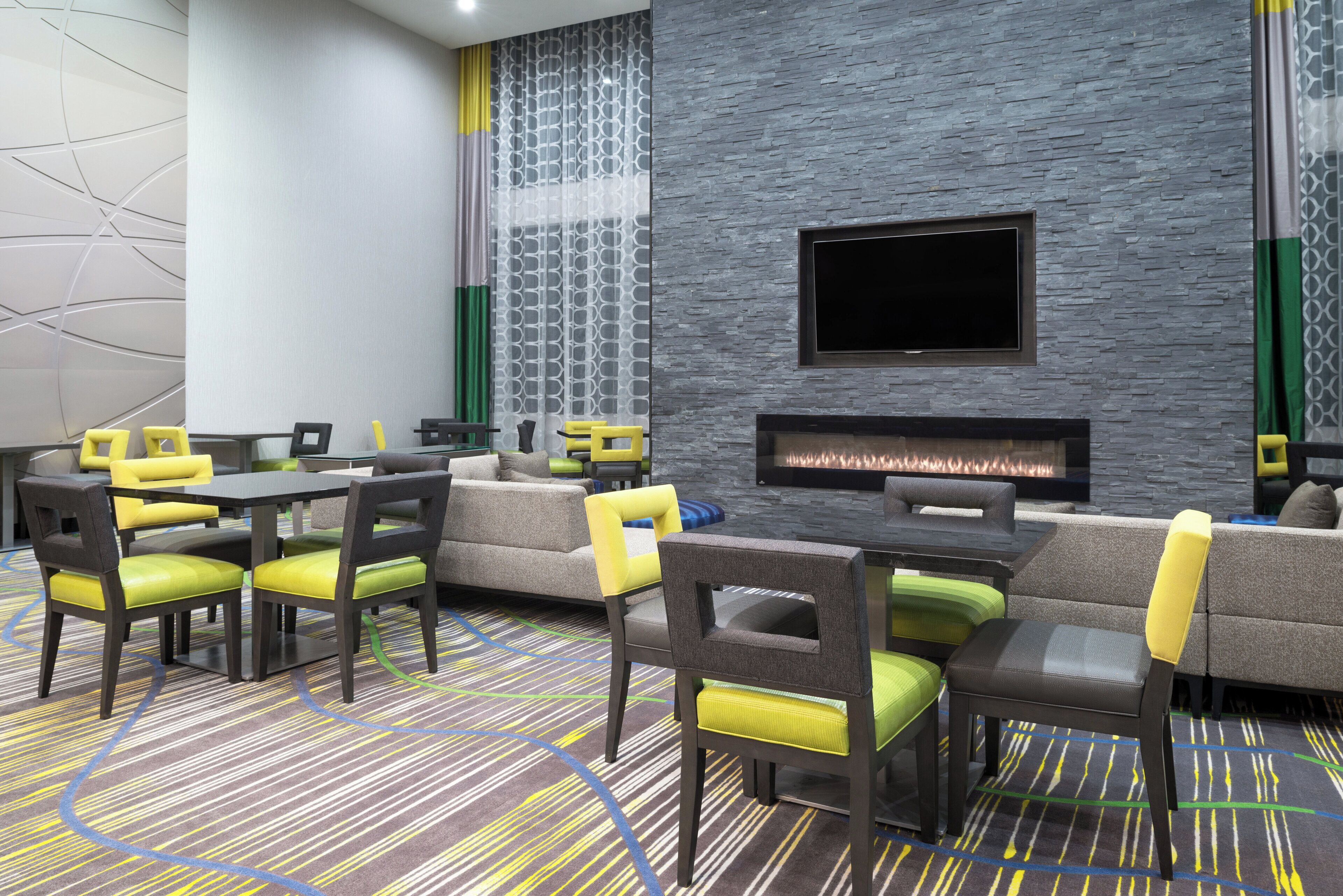 A modern lounge area with sofas, chairs, a flat-screen TV, and a fireplace.