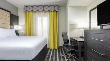 Une chambre d’hôtel comprenant un lit, un bureau, une chaise, une commode et un téléviseur.