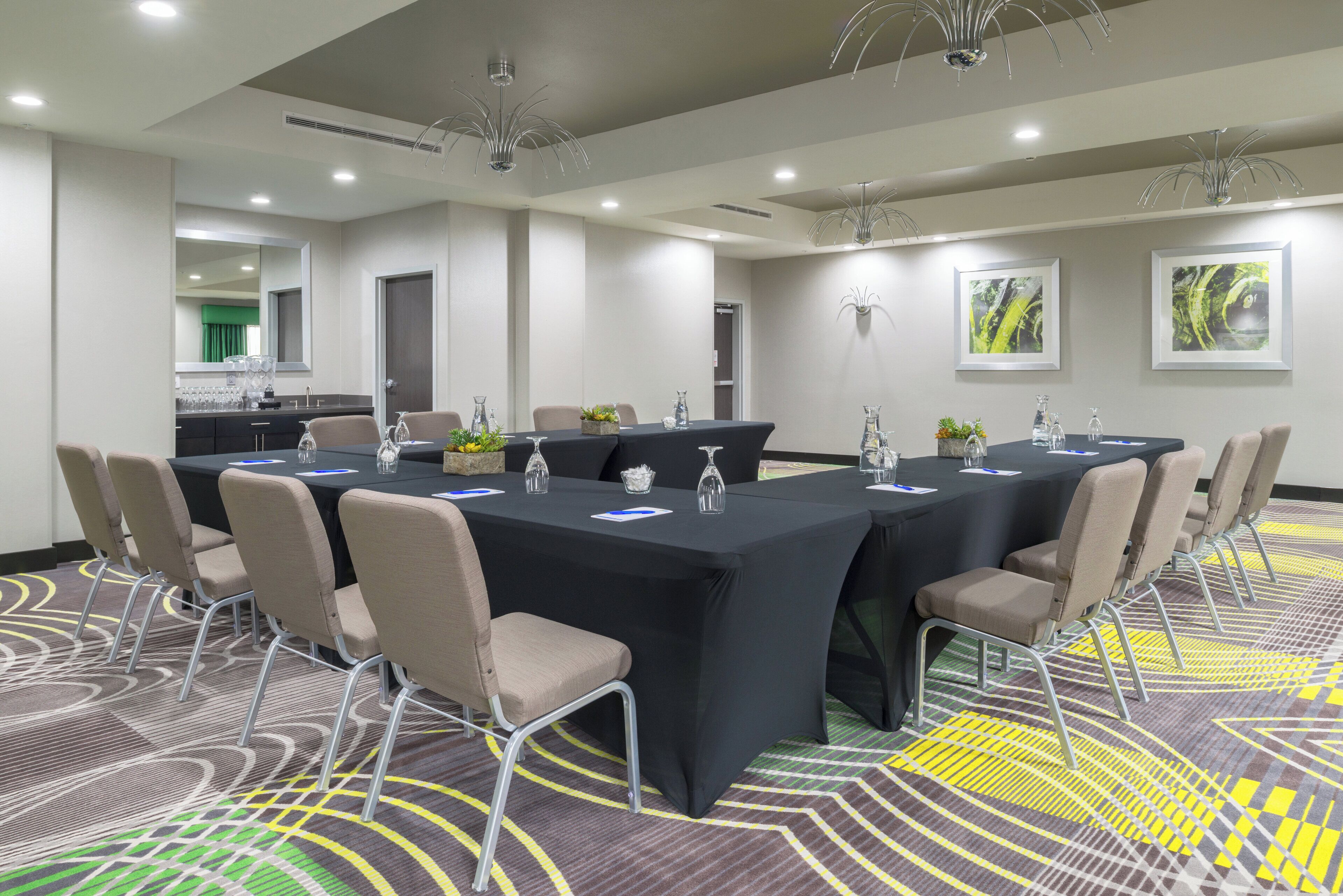 A conference room with a long table, chairs, and a carpeted floor.