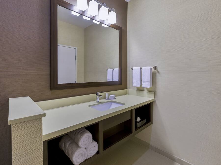 A modern bathroom with a white sink, a large mirror, and two towels hanging on a towel rack.