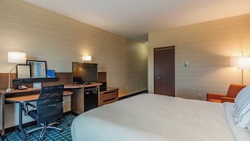 Une chambre d’hôtel avec un grand lit, un bureau équipé d’un ordinateur et d’une chaise, une télévision et deux lampes de chevet.