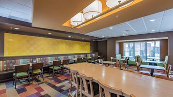 A conference room with a large table, multiple chairs, and a colorful carpet.