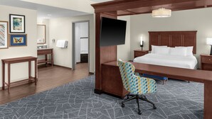 A hotel room with a bed, a desk, a chair, a television, and a bathroom visible through an open door. - Hampton Inn & Suites Coconut Creek (Coconut Creek)