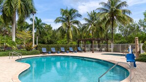 A swimming pool with lounge chairs and palm trees. - Hampton Inn & Suites Coconut Creek (Coconut Creek)