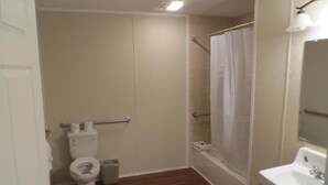 A bathroom with a toilet, a shower with a curtain, and a sink.