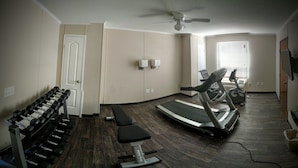 A home gym with a treadmill, dumbbells, and a bench.