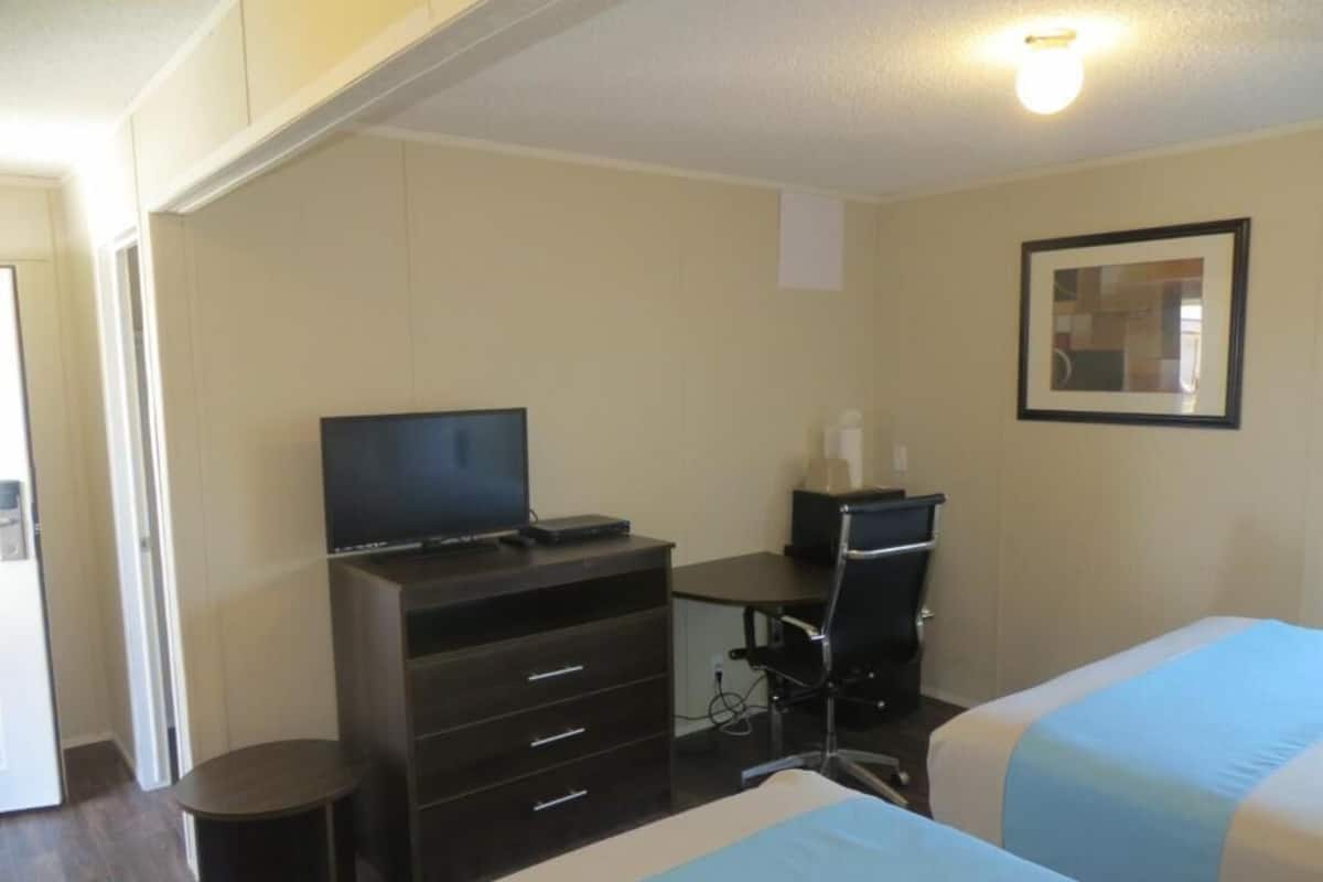 Ett hotellrum med en säng, ett skrivbord med en tv, en stol och ett litet bord.