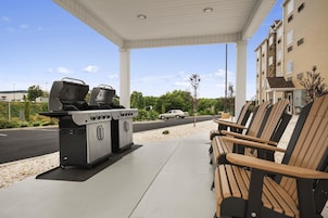 Zona de barbacoa al aire libre con parrilla y asientos.